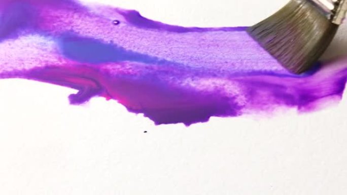 艺术家用紫色和蓝色水彩颜料在白纸上绘画，特写。水彩颜料纹理