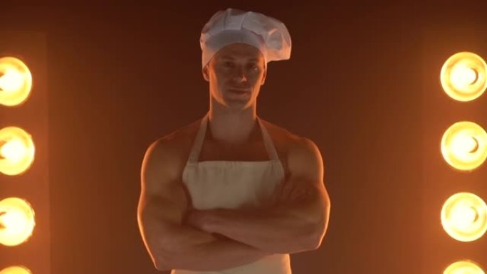肌肉厨师的肖像穿着白色围裙和厨师帽在烟雾缭绕的背景