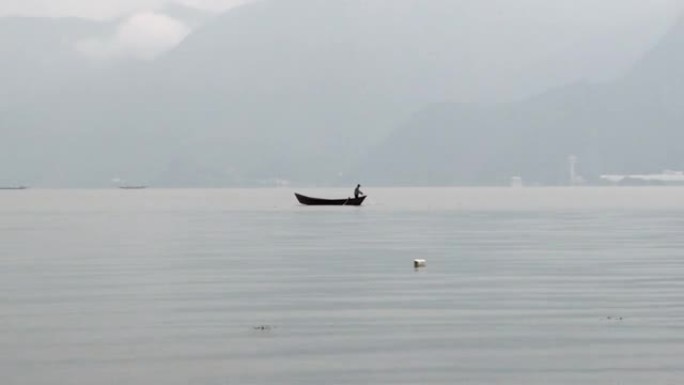 在中国抚仙湖，船上的渔民在雾中用渔网捕鱼。