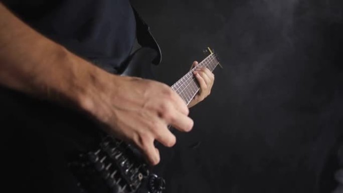 穿着黑色衣服的无法识别的摇滚音乐家在黑色背景上演奏黑色电吉他，与世隔绝。