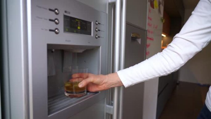 冰箱门中的制冰机将玻璃装满冰