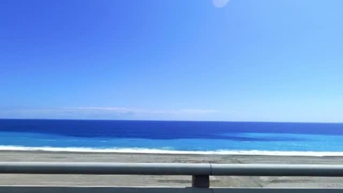POV-乘客侧窗驾驶场景。蓝色的海洋对抗蓝天