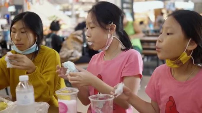 快乐的亚洲儿童在美食广场与家人一起谈论和分享棉花糖，bme小吃，生活方式理念。