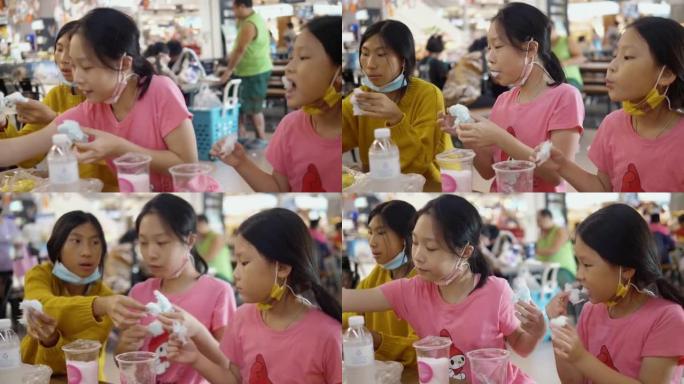 快乐的亚洲儿童在美食广场与家人一起谈论和分享棉花糖，bme小吃，生活方式理念。