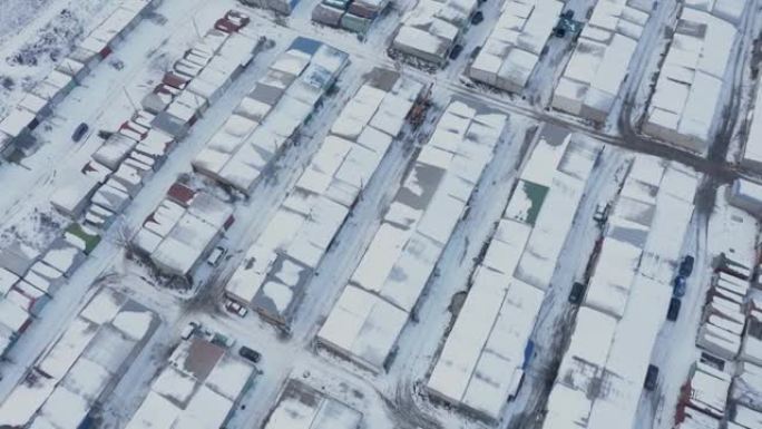 在冬天的日子里，在一个受保护的停车场里，一排排汽车车库的屋顶鸟瞰图。
