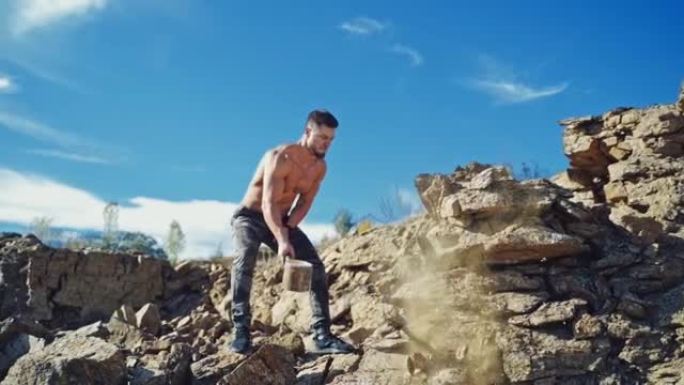 强壮的人正在用重锤训练。运动运动员在天然岩石背景上用铁锤打碎石头。慢动作。