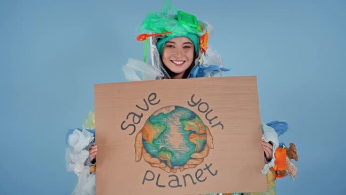 女人拿着带有铭文的纸板拯救你的星球。穿着垃圾服。