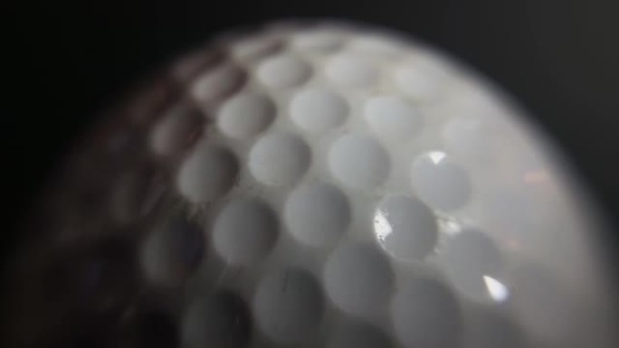 慢动作，黑色背景旋转的高尔夫球的极端特写镜头