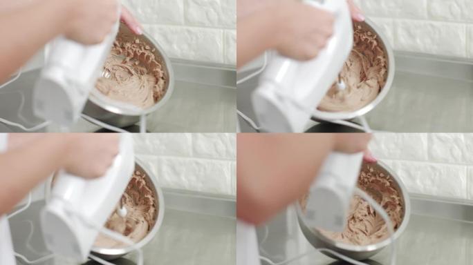 女性专业糖果手拿着手动搅拌器，浸入巧克力黄油奶油中。打奶油给甘纳奇。烘焙工艺阶段