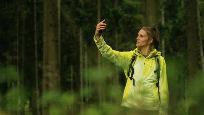 女人在森林里拍摄自己。穿越树林徒步旅行。多雨徒步穿越大自然。