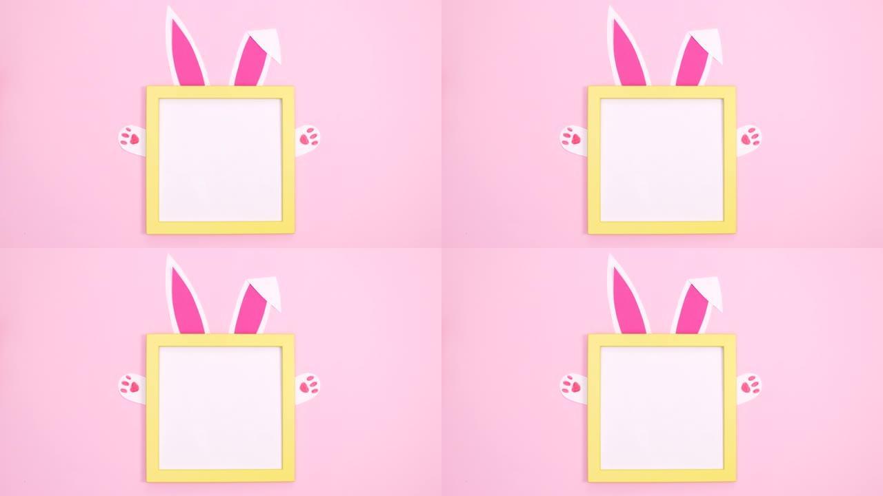 创意黄色复制空间框架，兔子耳朵和爪子在柔和的粉色背景上移动。停止运动最小平铺