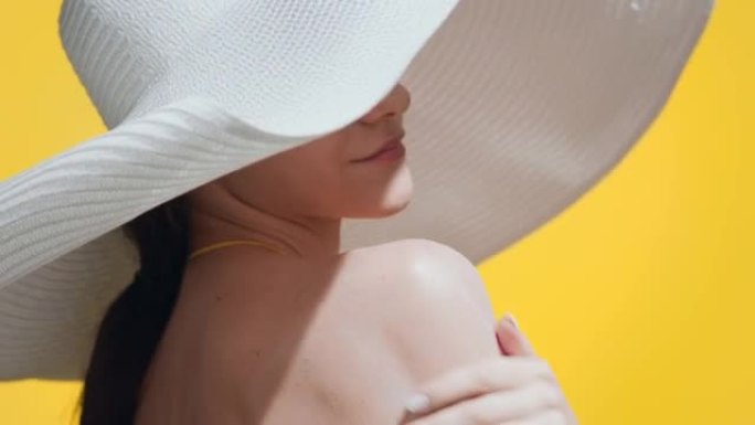 女人在肩膀上涂抹防晒霜，转身享受阳光