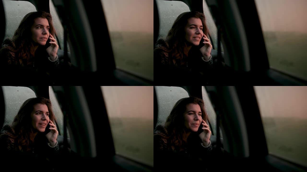 年轻女子在外面下雨时在车内打电话。