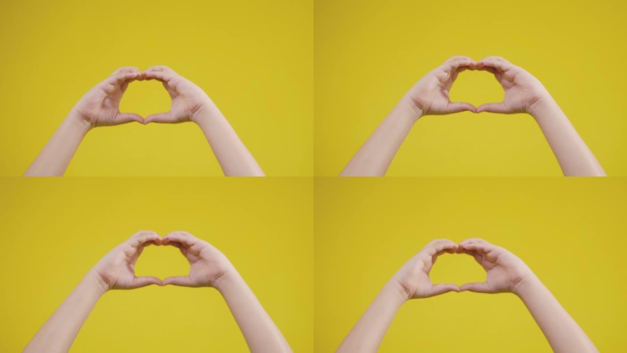 双手标志意味着黄色背景上的爱，生活方式的概念。