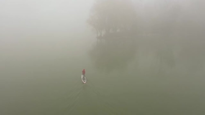 一个人在浓雾中漂浮在河上的木板上