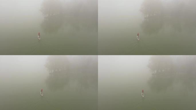 一个人在浓雾中漂浮在河上的木板上