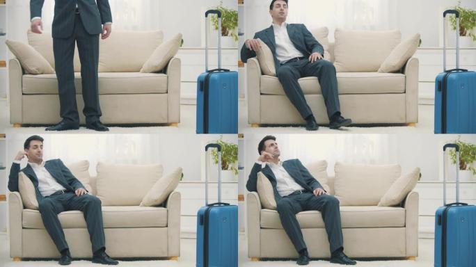 男人带着手提箱到达酒店房间，坐在沙发上看起来很累。