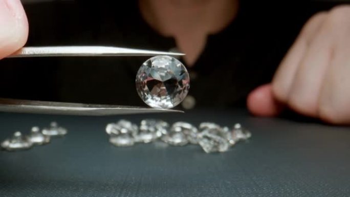 宏观: 珠宝商拿着一颗钻石，镊子显示特写。