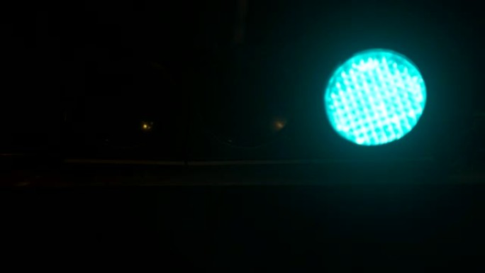 交通信号灯在晚上从绿色切换到红色。垂直悬挂交通灯
