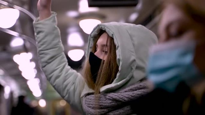 穿着温暖的女人在地铁车厢里戴口罩