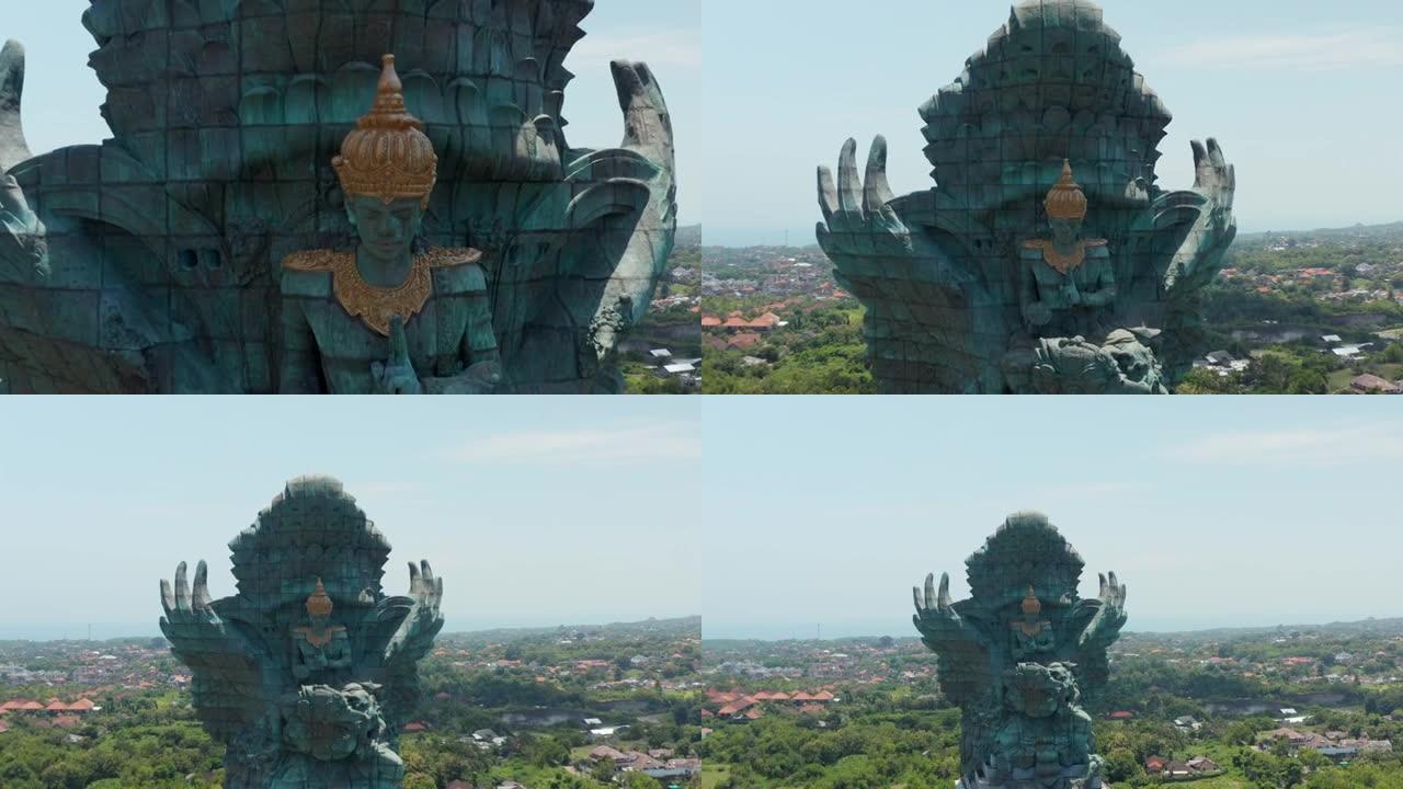 印度尼西亚巴厘岛公园内鹰航Wisnu Kencana雕像的特写视图，上升到城市上方。空中撤退揭示了印