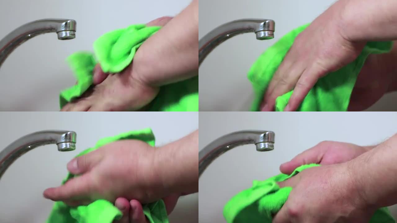 男人的手用绿色毛巾擦干。