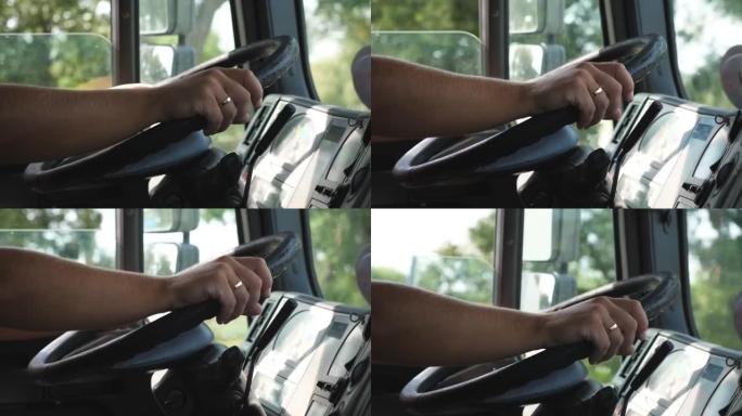 卡车司机的男性手握着一个大方向盘，同时骑着卡车穿过乡村。卡车司机在乡间小路开车到目的地。物流运输概念