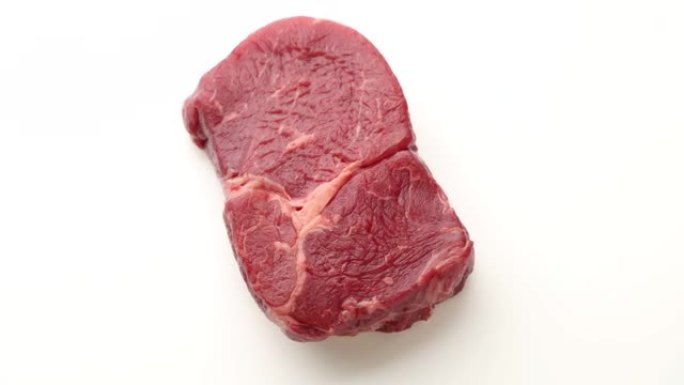 在白色背景上翻转生牛肉牛排肉的特写镜头，顶视图