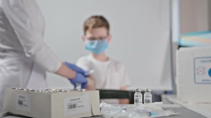 在一家现代诊所，由一名年轻护士接种一名小男孩的冠状病毒疫苗。疫苗接种过程引入抗体以产生针对冠状病毒的