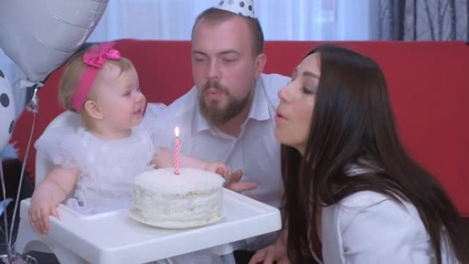 全家福妈妈，爸爸在女婴的一岁生日时在蛋糕上吹蜡烛。