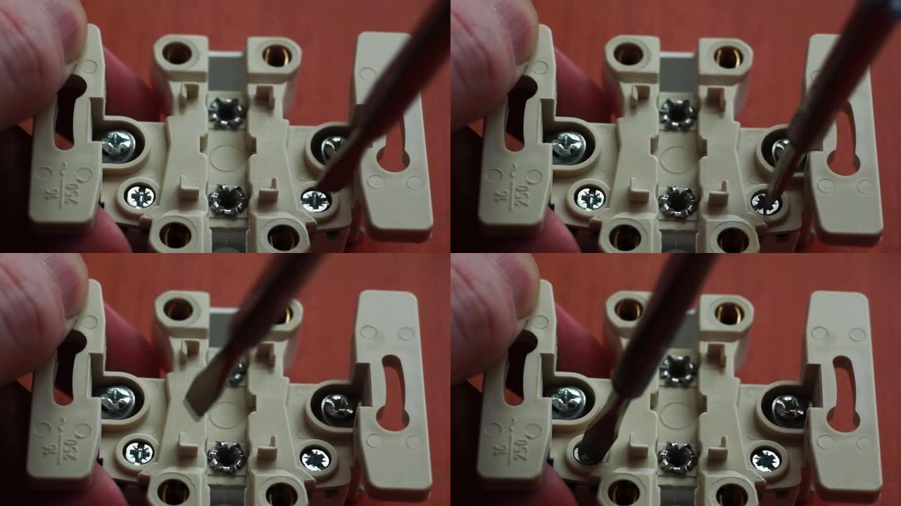 螺丝刀的特写镜头松开了电源插座上的螺钉。电气设备的安装。自制家庭维修