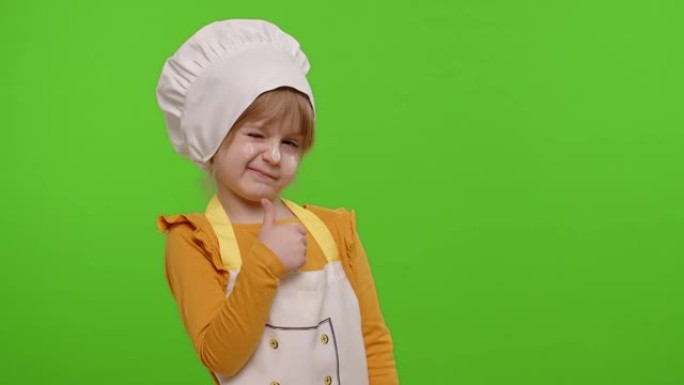 儿童女孩穿着围裙和帽子的厨师贝克，露出大拇指，在色度键上鬼混