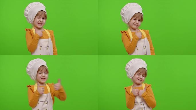 儿童女孩穿着围裙和帽子的厨师贝克，露出大拇指，在色度键上鬼混