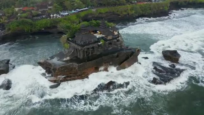 印度尼西亚巴厘岛波涛汹涌的海洋悬崖上的丹那洛特神庙令人惊叹的建筑的空中旋转俯视图
