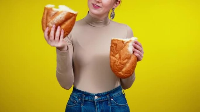 面目全非的年轻苗条女人撕着面包，吃美味的面包店。白人红发女士在黄色背景下享受美味的乡村糕点