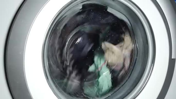 通用家用洗衣机中的衣物洗涤。旋转洗衣机滚筒的特写视频。