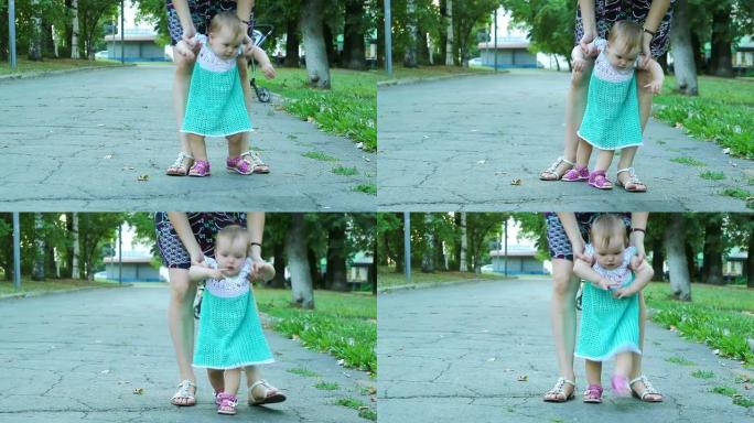 孩子的第一步。妈妈教走路，用手支撑女孩