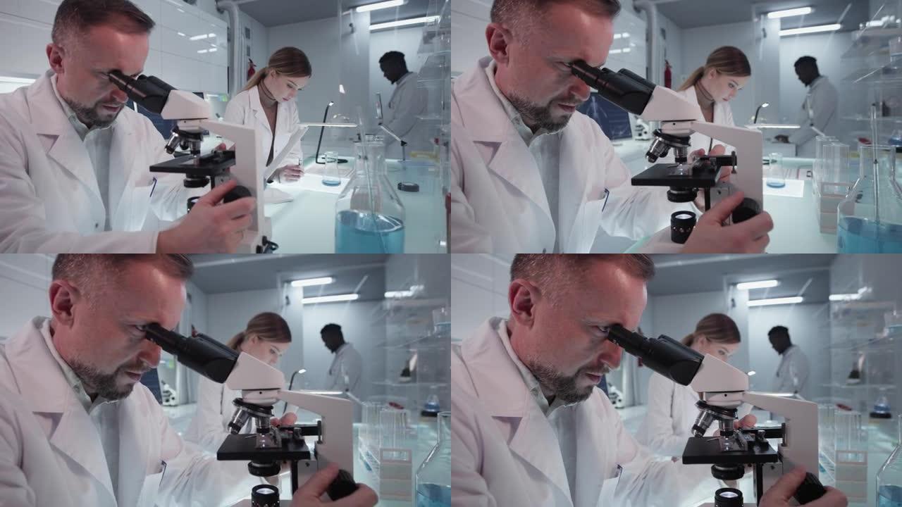 研究医学样本的多样化科学家。使用计算机和显微镜。现代实验室室内