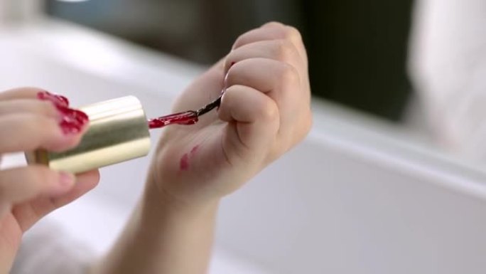 一个小女孩用鲜红色的清漆涂自己的指甲。