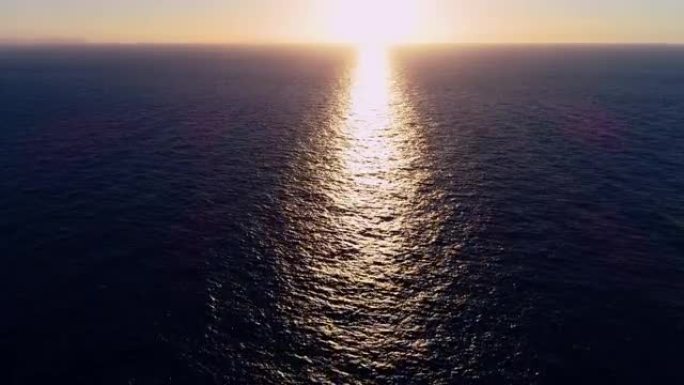 鸟瞰图，一艘帆船的无人机在日落下在地中海中部航行。我们可以看到整个地平线上的船和水以及水中光线的反射