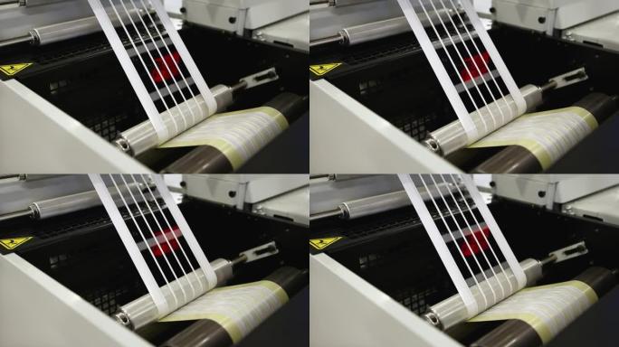 柔印机上标签制造的特写视频。在印刷行业中，柔性版印刷机上从粘合材料上去除基质废料或修剪的细节。