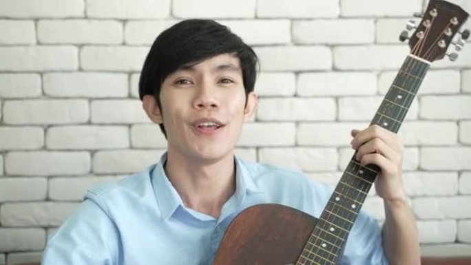 年轻的亚洲男子弹吉他音乐，唱一首歌放松录制视频直播，音乐家艺术家在家工作，网络空间的新常态生活方式在