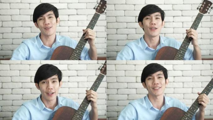 年轻的亚洲男子弹吉他音乐，唱一首歌放松录制视频直播，音乐家艺术家在家工作，网络空间的新常态生活方式在