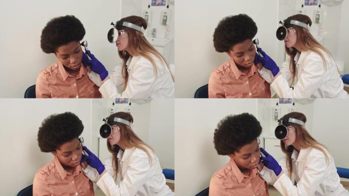 耳鼻喉科医生。非裔美国女医生。耳鼻喉科医生检查一个抱怨疼痛的女孩的耳朵。疼痛缓解和治疗理念。耳道或鼓