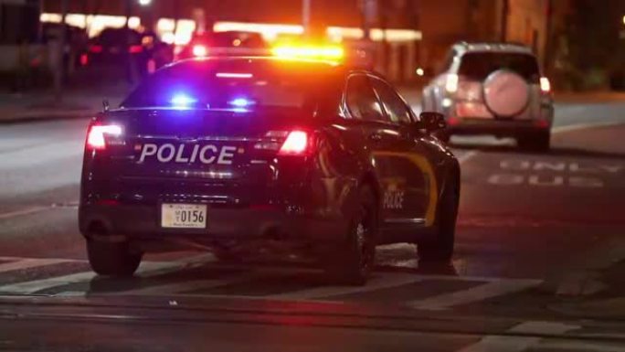 巴尔的摩市街道和夜间警用车灯。警察在公交专线上拦下了不知名的车辆。马里兰州