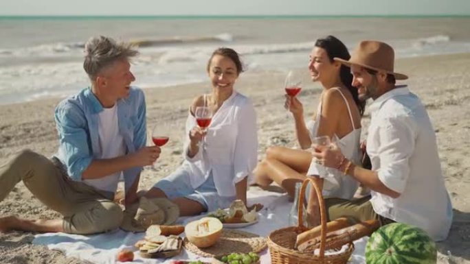 人们在海滩野餐派对上喝酒欢呼。人们举手举杯酒，在海边享受户外野餐