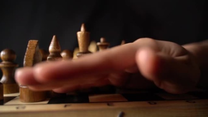 棋盘上两排白色棋子的特写。女人的手从黑色背景的棋盘上转移木制人物。慢动作