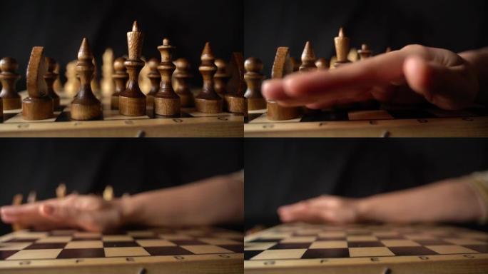 棋盘上两排白色棋子的特写。女人的手从黑色背景的棋盘上转移木制人物。慢动作