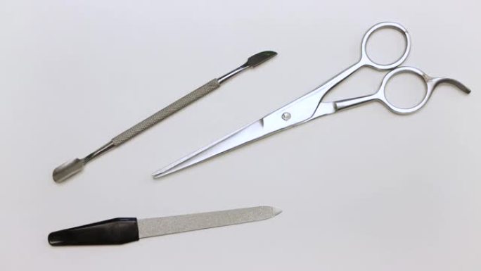 特写镜头中的一个人拿着剪刀，钳子，刮刀和指甲锉。