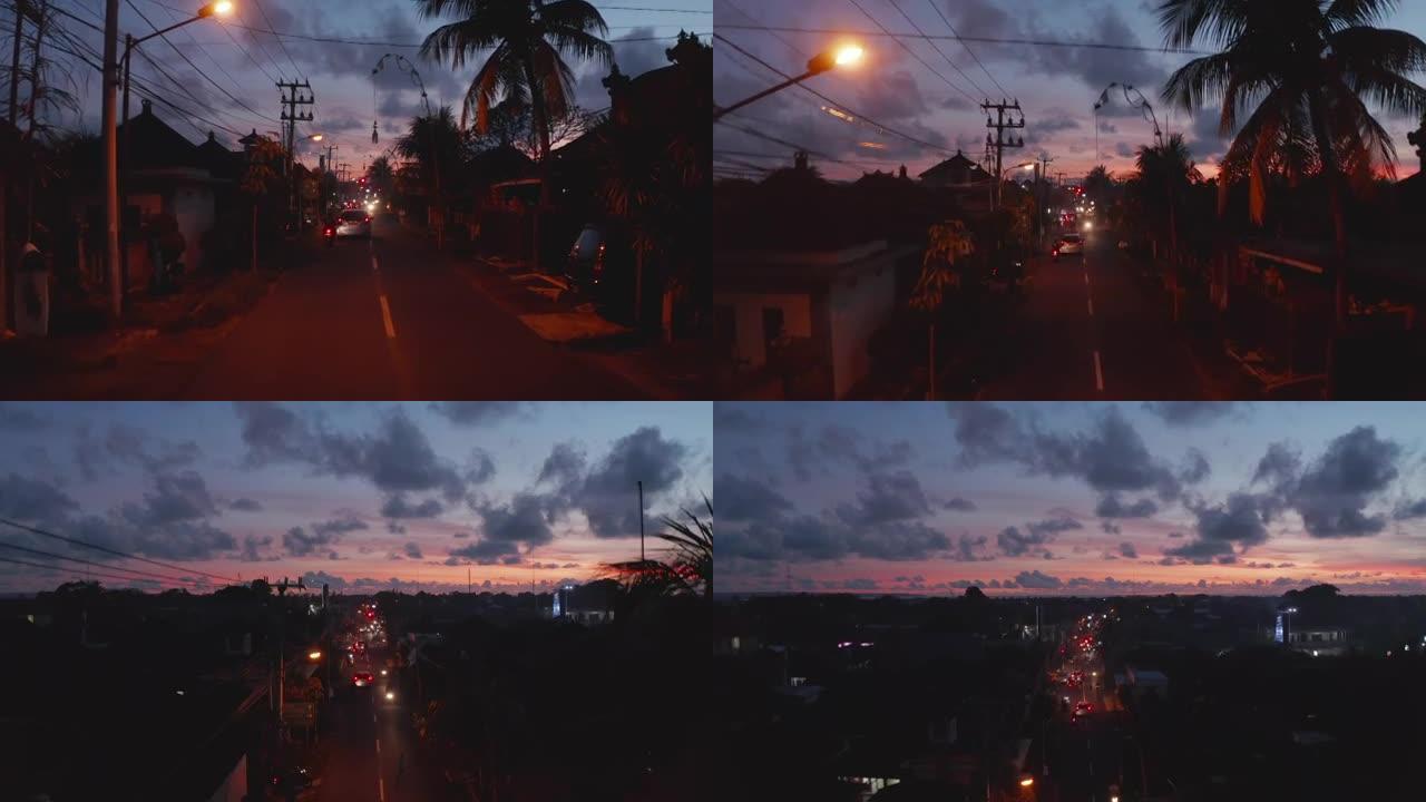 日落时热带巴厘岛街道的城市交通街景。印度尼西亚夜间街道上交通的上升鸟瞰图
